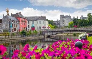 Kilkenny, Ireland - August 5, 2014: beautiful flower lined riverside view of kilkenny castle town and bridge